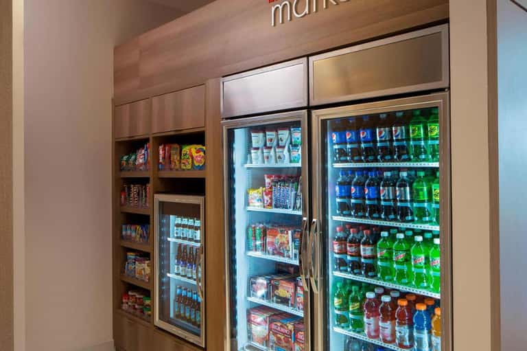 Market kiosk with refrigerated vending machines stocked with beverages and snacks