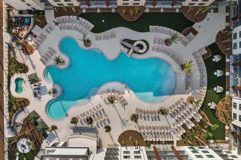 Aerial view of resort's curved pool complex surrounded by lounge chairs and palm trees