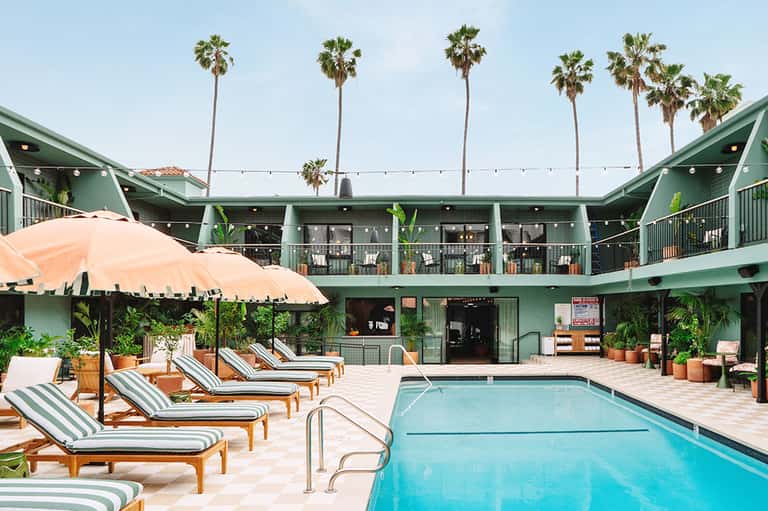 Resort pool courtyard with striped lounge chairs and green building architecture