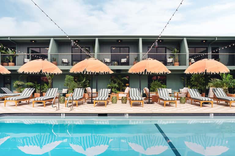 Resort pool with striped loungers, orange umbrellas, and modern building