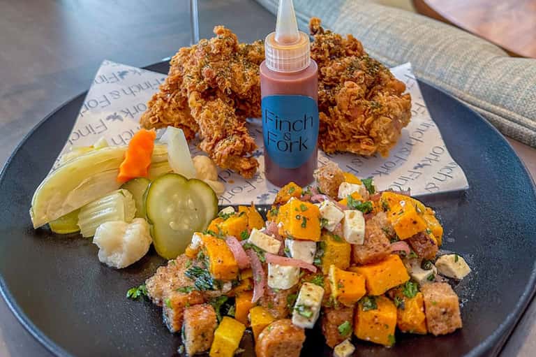 Gourmet plate with fried chicken, spiced hash, pickles, and hot sauce at upscale restaurant