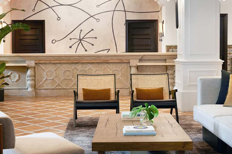 Modern hotel courtyard with abstract wall art, wooden chairs, and geometric stone flooring