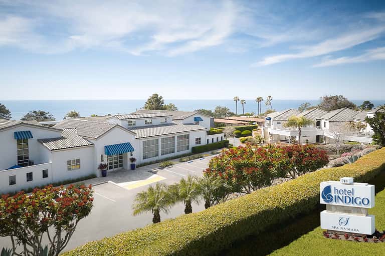 Hotel Indigo oceanfront property with white buildings, blue awnings, and manicured landscaping