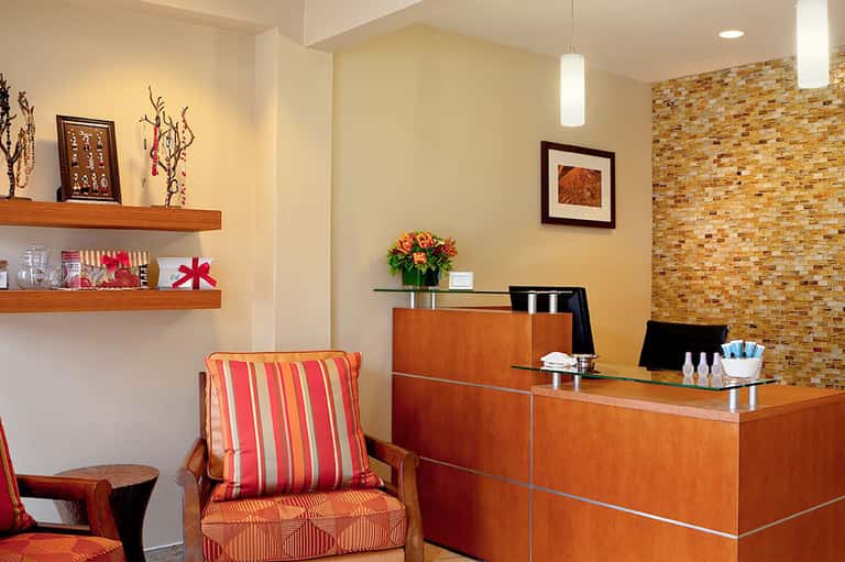 Hotel reception desk with warm wood tones, brick accent wall, and decorative shelving