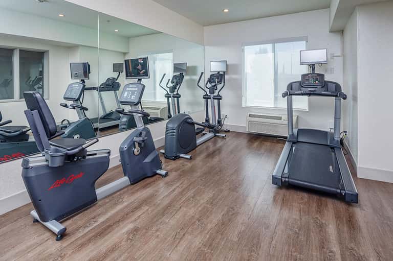 Modern fitness center with cardio equipment, exercise bikes, treadmill, and mirrored walls