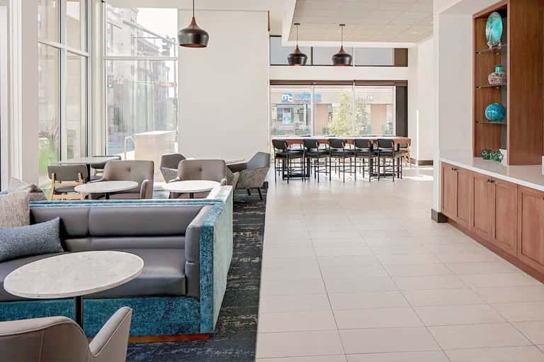 Contemporary resort lobby with teal accents, modern seating, bar area, and pendant lighting