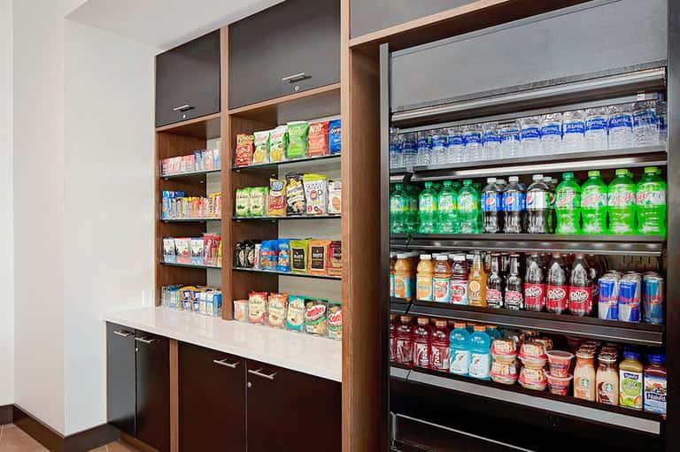 Convenience store snack area with wooden shelving, vending machine, and stocked beverages
