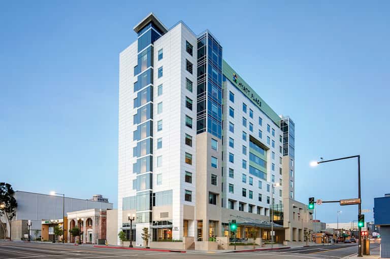 Contemporary multi-story hotel building with white and blue facade on urban street corner