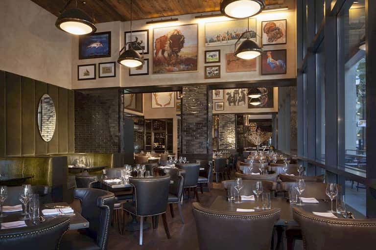 Contemporary steakhouse interior with artistic wildlife photography, leather seating, and pendant lighting