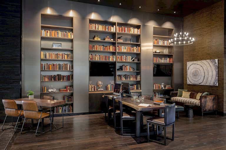 Upscale library lounge with floor-to-ceiling bookshelves, desk areas, and contemporary furnishings
