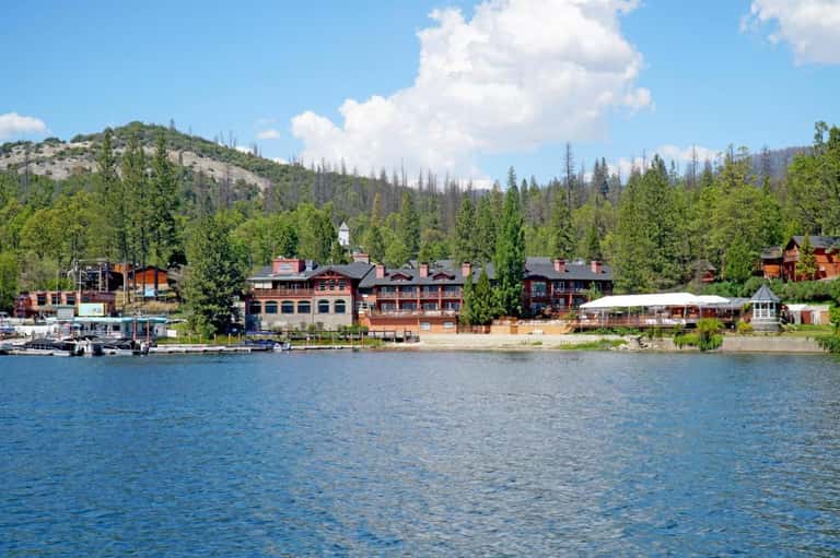 Lakefront resort with red buildings nestled in forested mountains with dock
