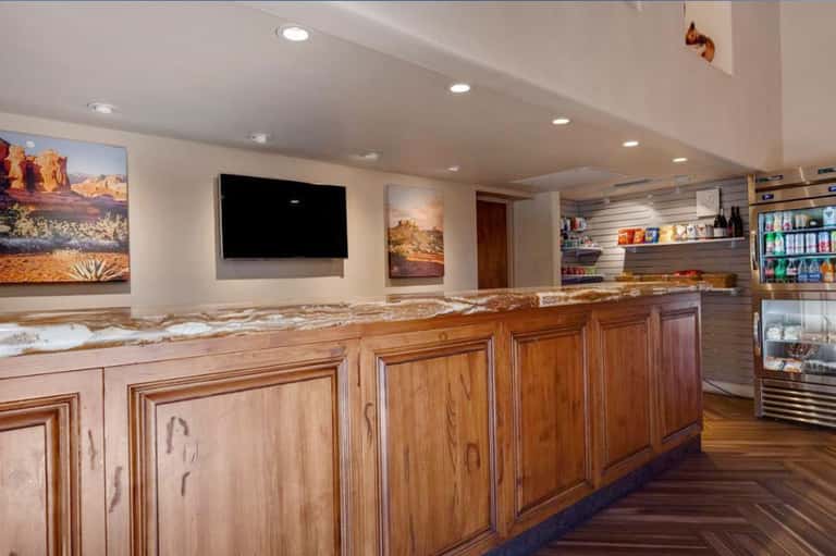 Resort bar and lounge interior with wooden cabinetry, granite countertop, TV, and beverage coolers
