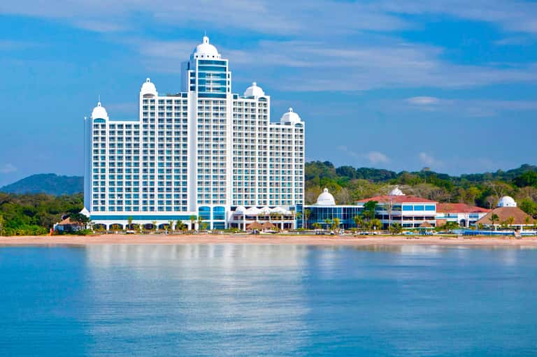 Beachfront resort with distinctive white multi-story architecture and dome rooftops overlooking turquoise water