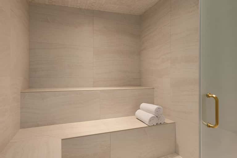 Luxurious bathroom with limestone tile steam shower and rolled white towels