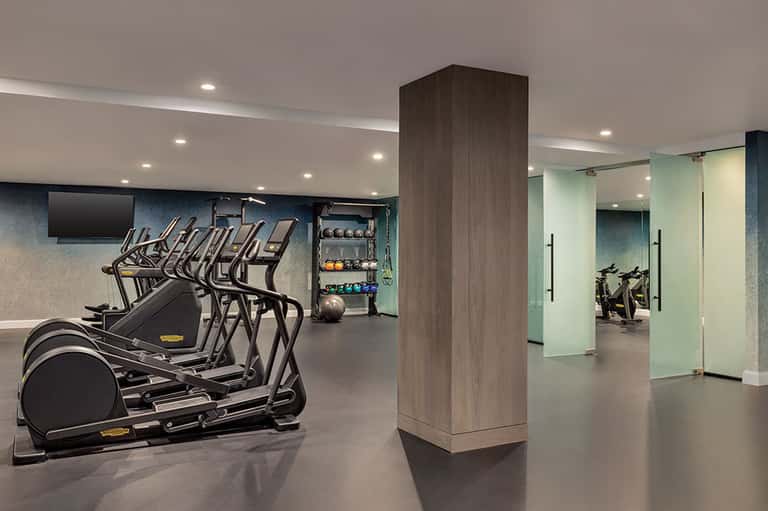 Contemporary fitness center with cardio equipment, weights, and glass-enclosed studio space