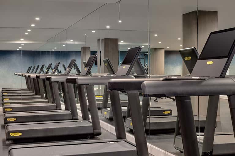 Modern gym interior with rows of treadmills, mirror walls, and contemporary lighting design