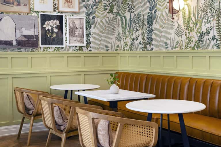Modern café interior with yellow-green paneling, botanical wallpaper, and contemporary seating