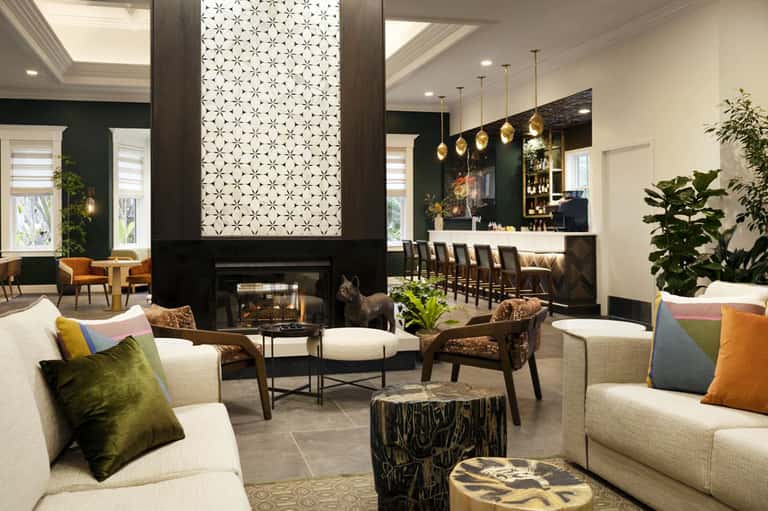 Upscale hotel lobby with fireplace, pendant lights, modern seating, and bar area