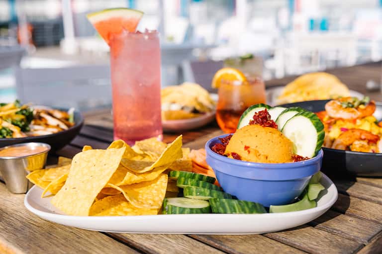 Gourmet poolside dining with cocktails, tacos, and appetizers on wooden deck