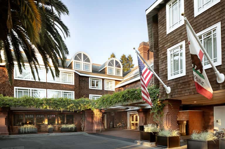 Historic brick hotel exterior with arched windows, American flag, and landscaped entrance courtyard