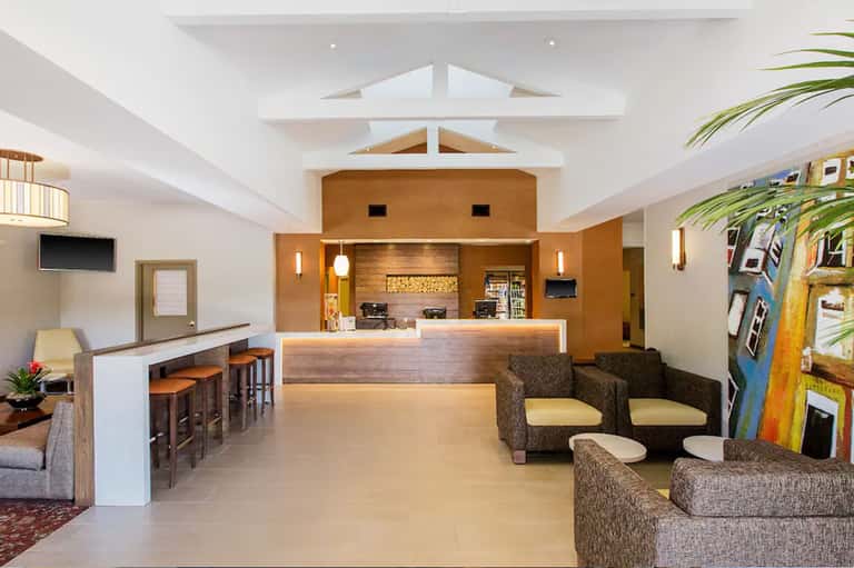 Modern hotel lobby with high ceilings, warm wood reception desk, and contemporary furnishings
