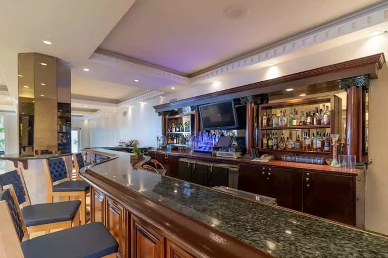 Upscale hotel bar with dark wood cabinetry, granite counter, and liquor bottle display