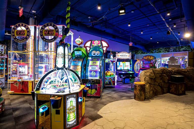 Colorful arcade games and machines in a brightly lit indoor entertainment venue