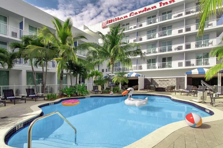 Garden Inn resort courtyard with palm trees, swimming pool, and multi-story hotel building