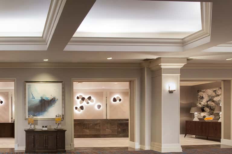 Elegant hotel corridor with skylights, marble accents, artistic wall fixtures, and modern decor