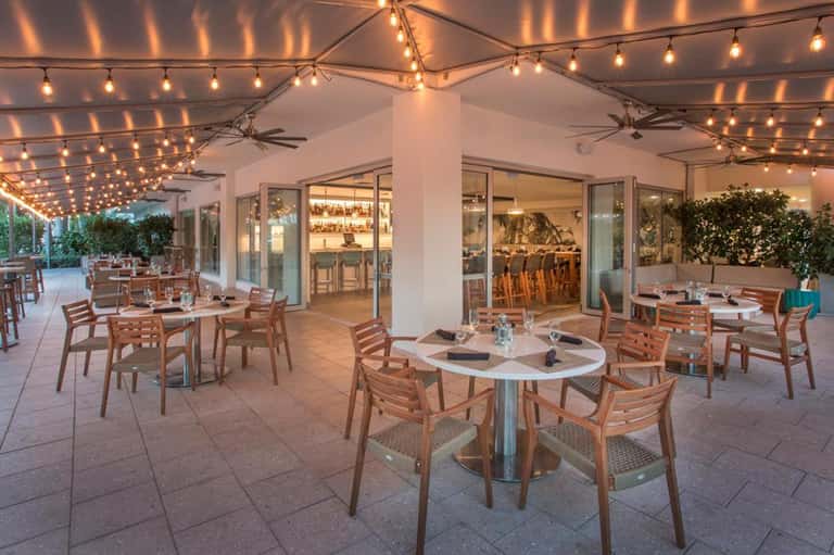 Outdoor restaurant patio with string lights and wooden chairs