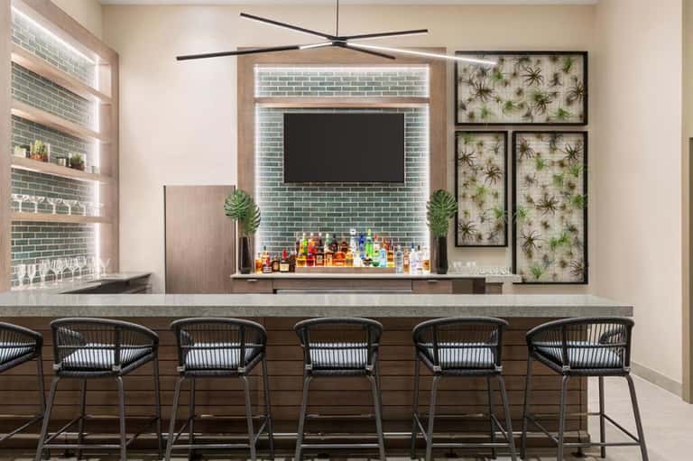 Contemporary bar with geometric ceiling fan, green tile backsplash, and tropical wall art