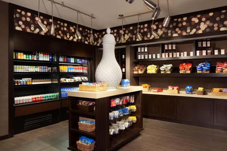Modern hotel convenience store with refrigerated beverages, snacks, and decorative lighting
