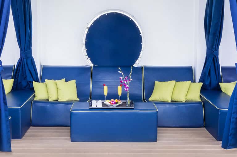 Modern pool cabana with blue seating, yellow pillows, and circular blue neon mirror accent