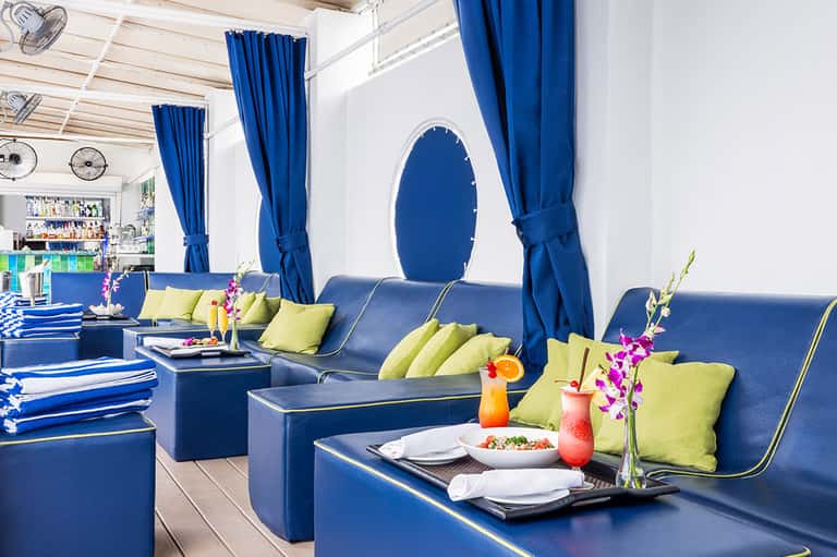 Blue and yellow lounge bar with plush seating, flowered centerpieces, and arched window