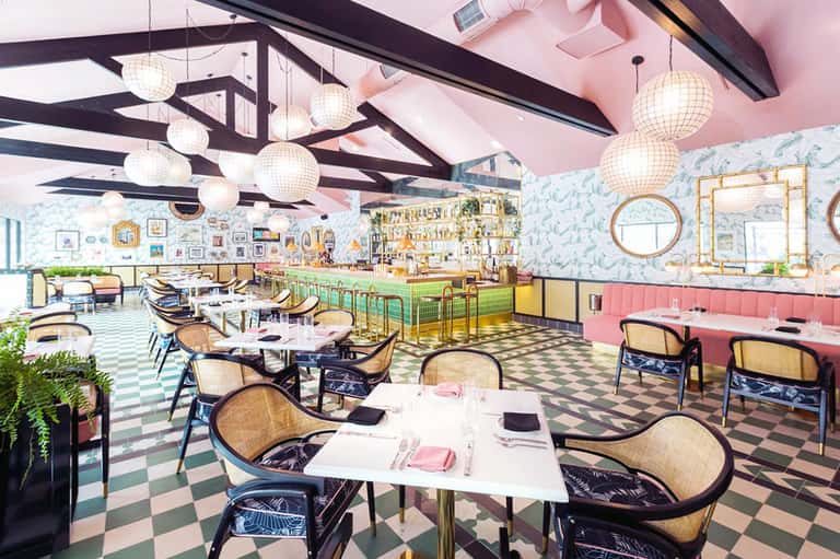 Colorful modern restaurant interior with pink ceiling, checkered floor, and hanging globe lights