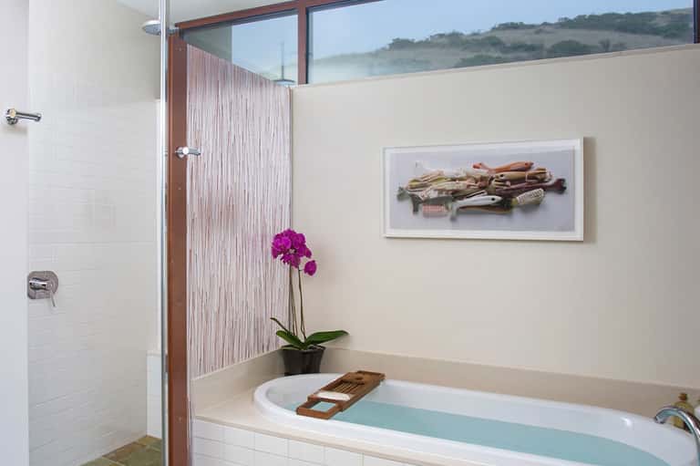 Luxury bathroom with soaking tub, rainfall shower, and scenic hillside window view
