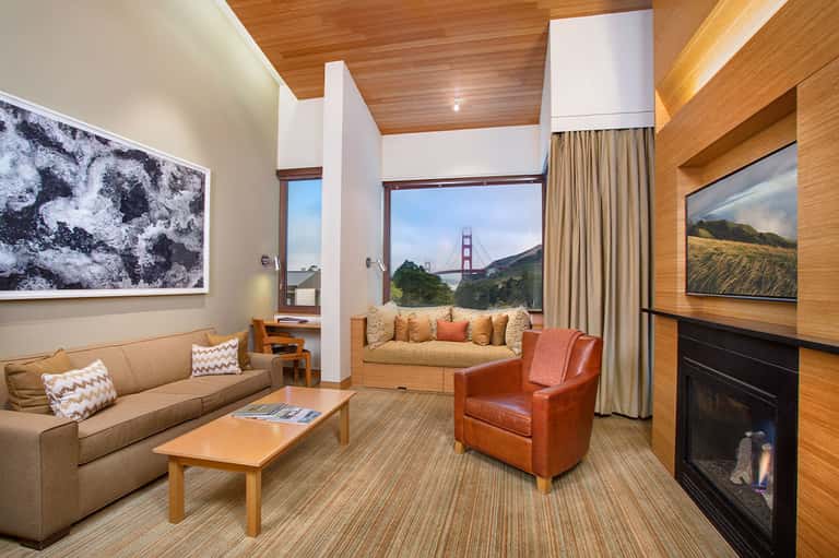 Upscale hotel suite with wood accents, fireplace, and floor-to-ceiling windows with bridge view