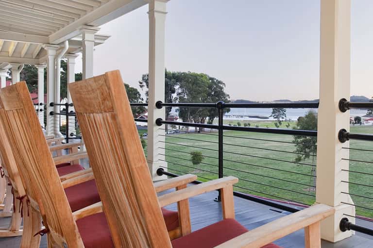 Wooden Adirondack chairs on elevated deck overlooking lake with railing