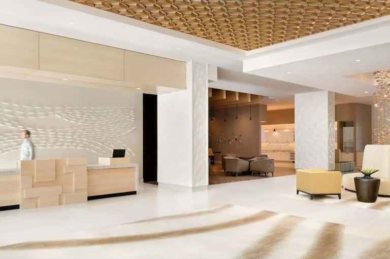 Modern hotel lobby with wooden ceiling details, reception desk, and seating