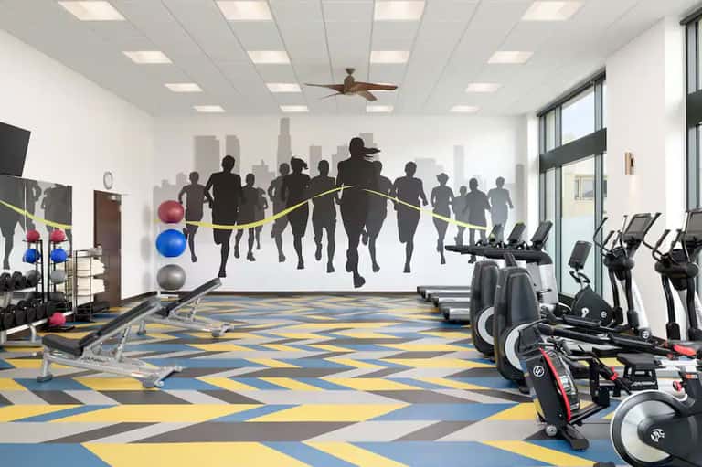Modern fitness center with exercise bikes, weights, and motivational mural of running athletes