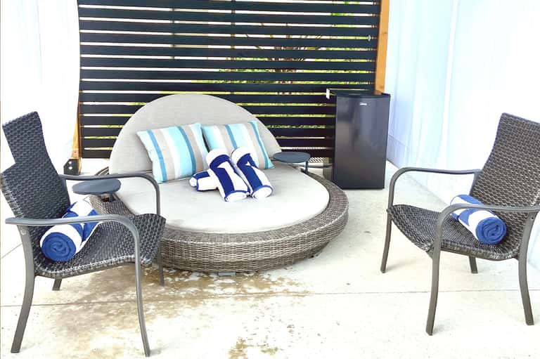 Circular outdoor seating area with rounded sofa, striped pillows, and slatted privacy screen