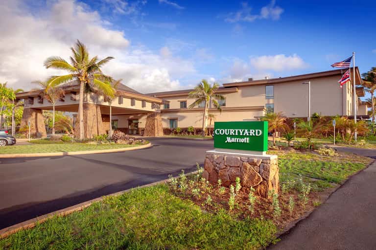 Courtyard Marriott entrance with palm trees, manicured lawn, and tropical landscaping