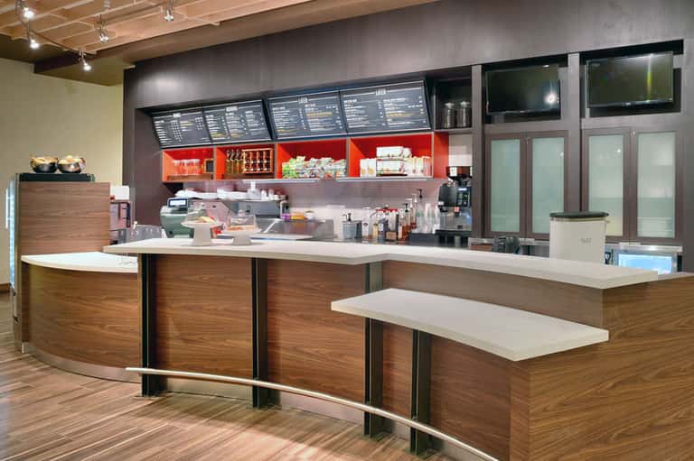 Contemporary hotel café counter with red accents, menu boards, and modern fixtures