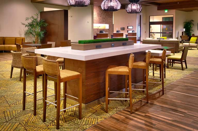 Modern hotel lobby bar with wooden counter seating and contemporary lighting
