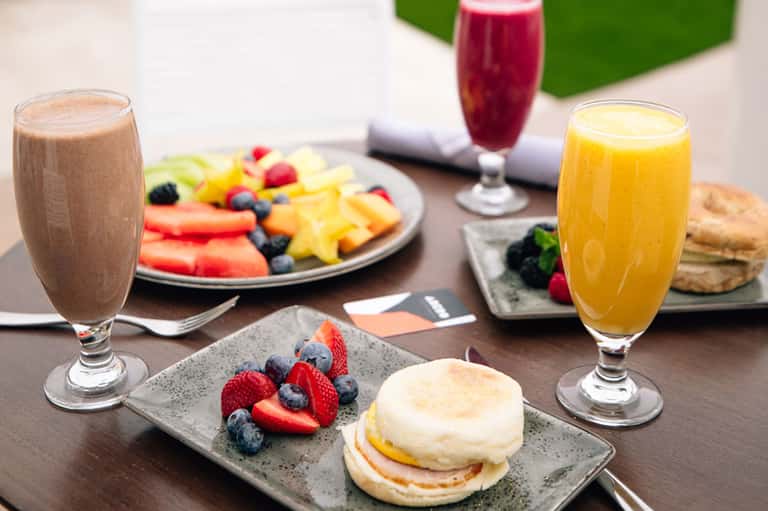 Breakfast spread with fruit, pastries, juices, smoothie, and berries on outdoor table