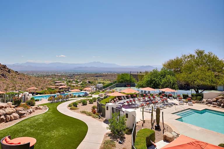 Desert resort pools, loungers, and mountain views under clear blue sky