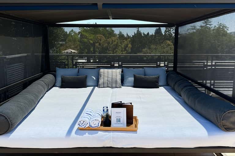 Luxury resort bed with ocean and forest views from covered outdoor platform