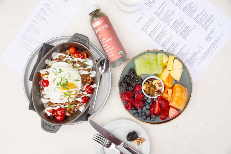 Healthy meal spread with fruit bowl, grain bowl, and organic beverages on white table