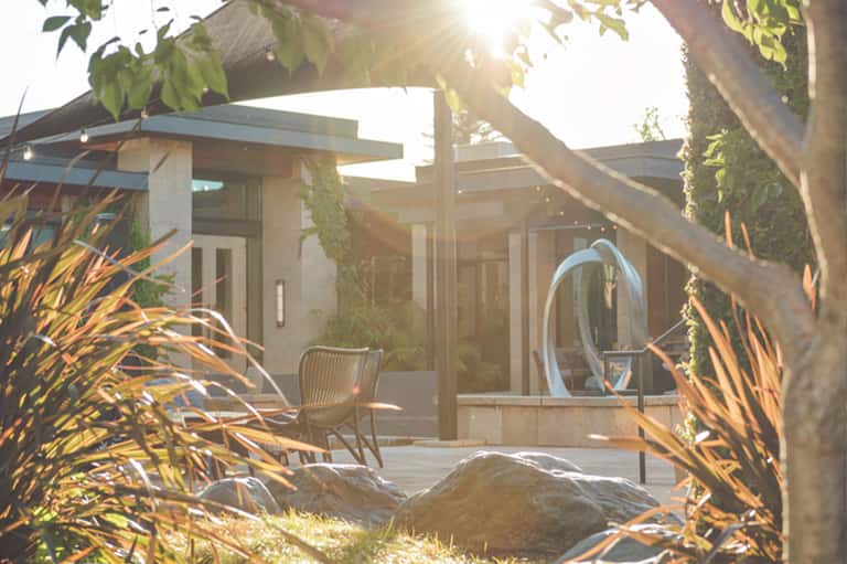 Modern patio lounge area with comfortable seating overlooking lush gardens at sunset