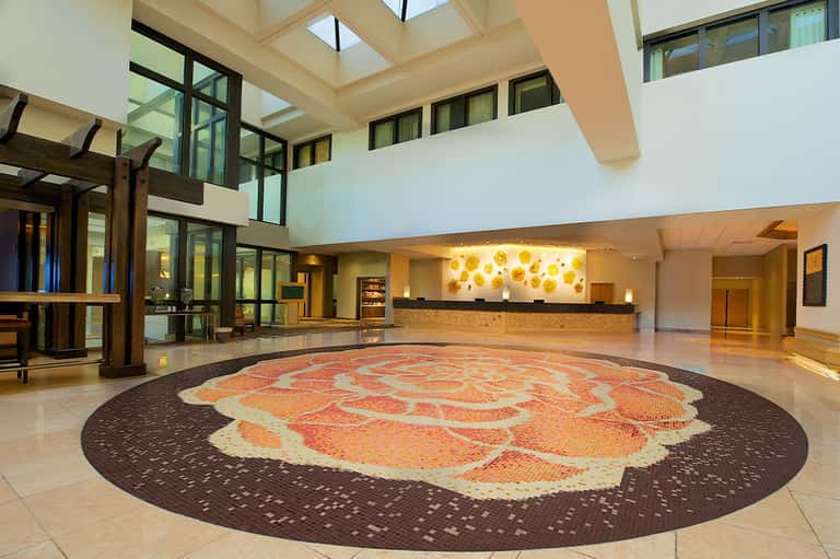 Spacious hotel lobby with soaring ceiling, architectural skylight, decorative circular floor pattern, and reception desk